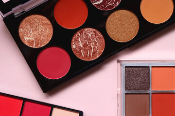 Various colorful eyeshadow palettes on bright pink background. Flat lay.