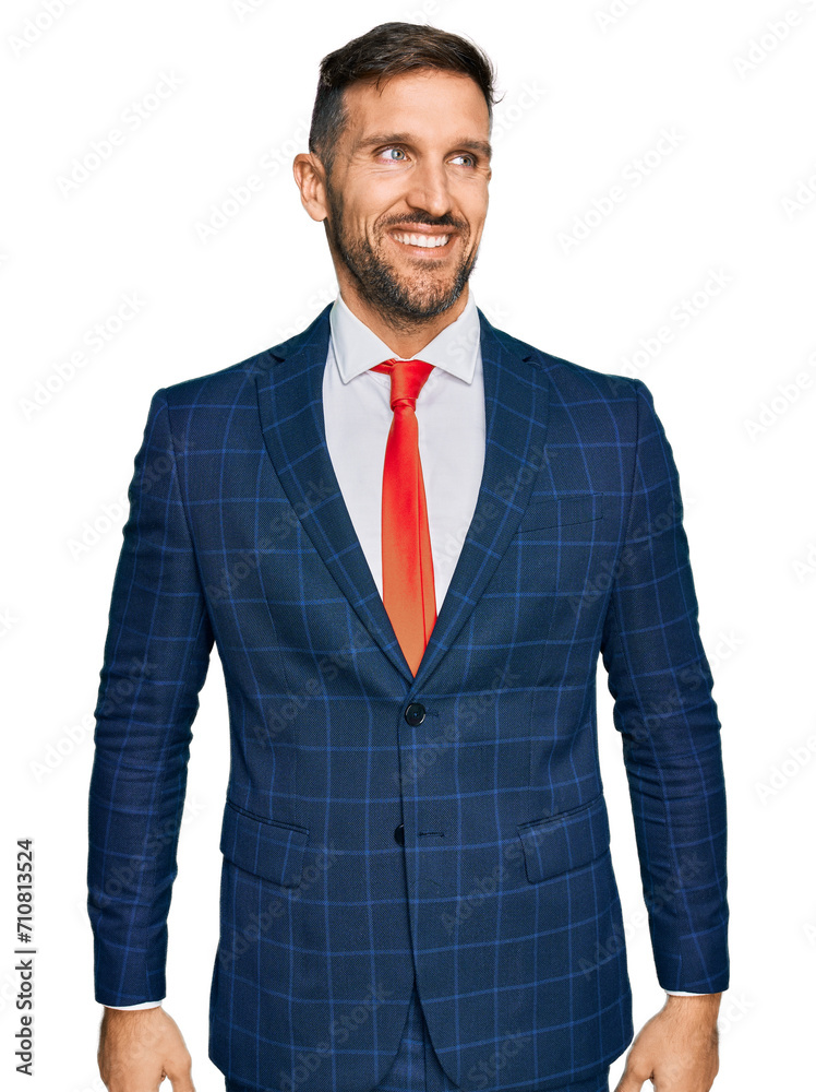 Poster Handsome man with beard wearing business suit and tie looking away to side with smile on face, natural expression. laughing confident.