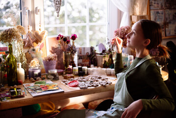 A girl gardener at home takes care of flowers by the window.