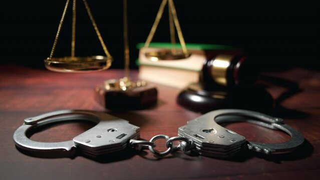 Close up of a judge gavel with handcuffs and a scales of justice. Legal lawyer books or codex. Criminal law or legal system and jurisprudence or court. Concept of crime or bribe and fraud.