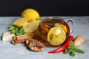 Hot tea with lemon, ginger, honey and mint on a dark background with copy pace. Homemade anti flu drink. Healthy eating concept. 