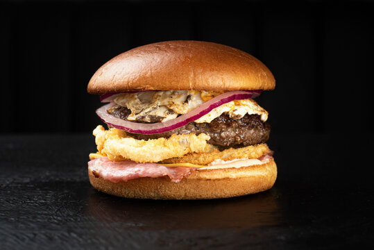 Hamburger on a black background with olives and fera cheese