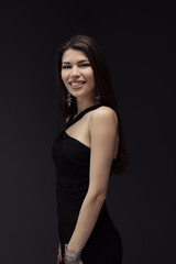 A woman elegantly poses in a classic black dress, ready to be captured in a memorable photograph.
