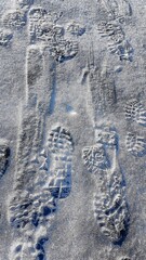 Naklejka premium Footprints on a frozen lake in the mountains during a January hike.