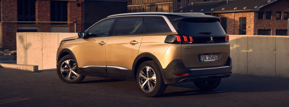Golden Peugeot 5008, 7 person SUV, in the parking lot in front of old  factory buildings. Katowice, Poland, 06.03.2017