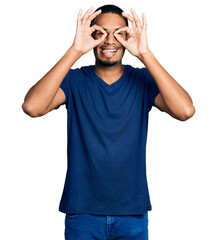 Young african american man wearing casual t shirt doing ok gesture like binoculars sticking tongue out, eyes looking through fingers. crazy expression.
