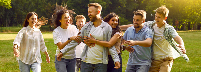 Portrait of a group of happy laughing people friends hugging in the summer park and smiling. Young...