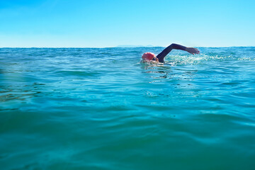 Swimming, stroke and person in ocean water in summer for exercise, training or workout on mockup space. Sea, sport and a young athlete outdoor for fitness, health and triathlon competition in nature