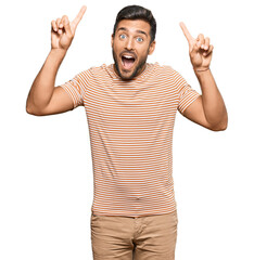 Fototapeta premium Handsome hispanic man wearing casual clothes smiling amazed and surprised and pointing up with fingers and raised arms.