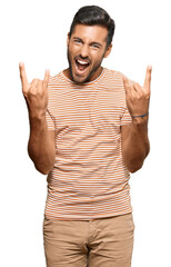 Handsome hispanic man wearing casual clothes shouting with crazy expression doing rock symbol with hands up. music star. heavy music concept.