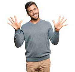 Handsome hispanic man wearing casual clothes showing and pointing up with fingers number ten while...