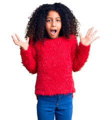 African american child with curly hair wearing casual winter sweater celebrating victory with happy smile and winner expression with raised hands