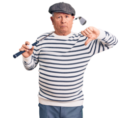 Senior handsome grey-haired man holding golf club and ball with angry face, negative sign showing dislike with thumbs down, rejection concept