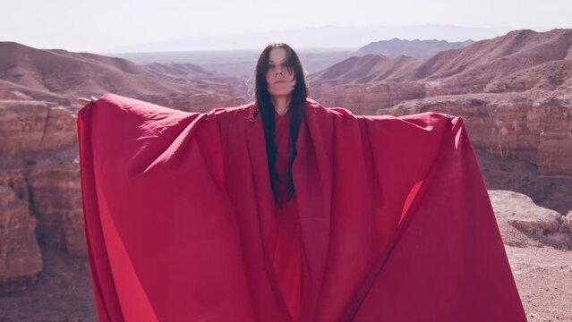 The girl in red over the canyon cliff. Slow motion.