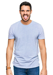 Young hispanic man wearing casual clothes sticking tongue out happy with funny expression. emotion concept.