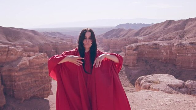 The girl in red over the canyon cliff. Slow motion.