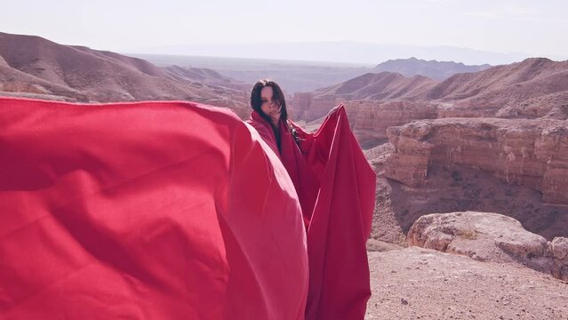 The girl in red over the canyon cliff. Slow motion.