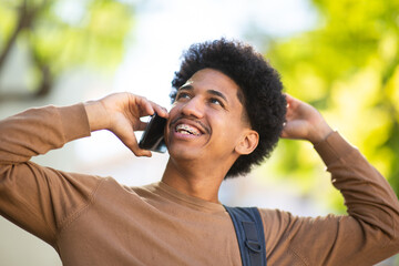 young African American man laughs while talking on his mobile phone