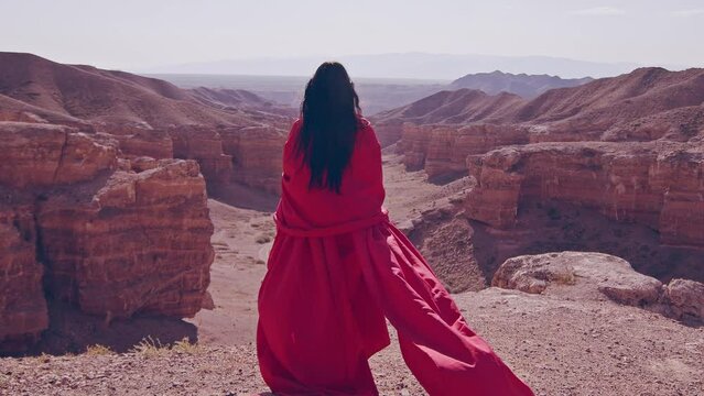The girl in red over the canyon cliff. Slow motion.
