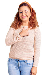 Young latin woman wearing casual clothes and diadem cheerful with a smile of face pointing with hand and finger up to the side with happy and natural expression on face