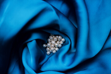 Natural milky freshwater pearls lie on blue silk fabric. freshwater pearl beads