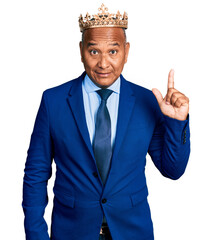 Hispanic middle age man wearing king crown pointing finger up with successful idea. exited and happy. number one.