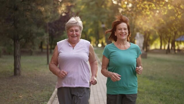 Two cheerful elderly ladies running at the park