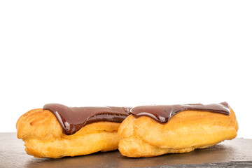 Two sweet chocolate eclairs on slate stone, close-up isolated on white background.