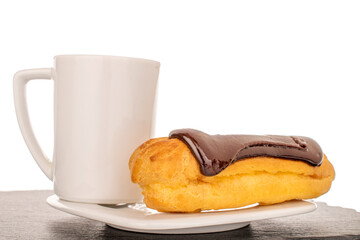 One sweet chocolate eclair on a white ceramic saucer with a cup on a slate stone, close-up isolated...