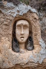 Fototapeta premium outdoor sculptured figure of human face and pair of on the wall by anonymous sculptor in Falces Navarra