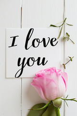 I love you card with pink peony on white wooden background.