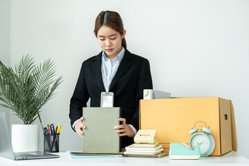 Business woman employee in suit packing notebook and picking up personal belongings into brown cardboard box
