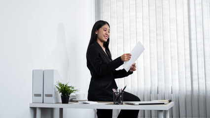 Young secretary woman looking on paper document to reading finance report