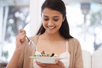 Happy woman, bowl and eating salad for diet, healthy snack or natural nutrition on sofa in living room at home. Female person, vegan or nutritionist smile with mix vegetables for weight loss at house