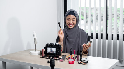 Asian muslim woman beauty blogger applies skin powder with brush and tutorial how to use cosmetic