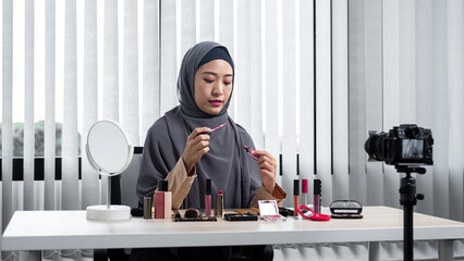 Asian muslim woman beauty blogger recommend and to review pink lipstick while recording vlog video
