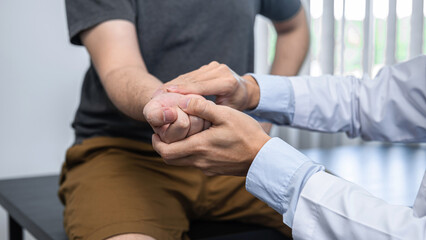 Young asian physiotherapist examining pulse of man patient by hands