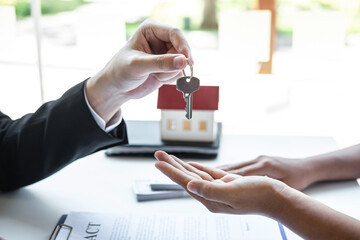Estate agent giving house keys to client after signing agreement contract real estate with approved mortgage application form, concerning mortgage loan offer for and house insurance
