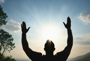 Silhouette of man worship with hands raised to the sky in nature