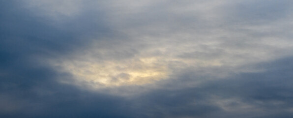 The faint light of the sun penetrates through the dark clouds