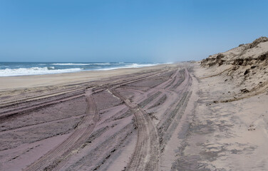 Fototapeta na wymiar tyre tracks on large sand beach at shore of Naukluft desert, Walvis Bay, Namibia