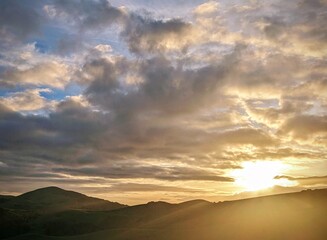 sunset colors paint the sky, as clouds float gracefully over the mountains