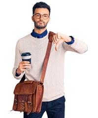 Young handsome hispanic man wearing leather bag and drinking take away coffee with angry face,...