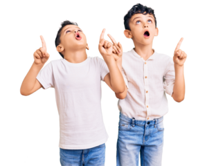 Couple of little brothers together wearing casual clothes amazed and surprised looking up and pointing with fingers and raised arms.