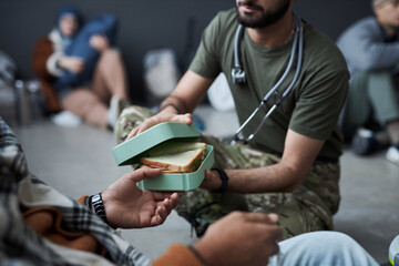 Close up of unrecognizable man giving food to Middle Eastern refugees while volunteering in...
