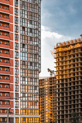 The concept of urban construction. Construction of multi-storey buildings. View of a multi-storey building against the blue sky. Vertical image. A newly built residential complex.