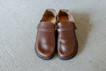 コンクリートの床に置かれた茶色の革靴,レザーシューズ