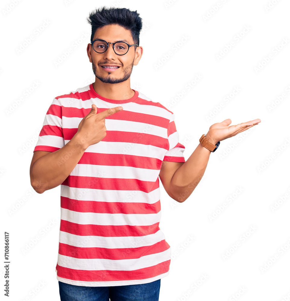 Wall mural handsome latin american young man wearing casual clothes and glasses amazed and smiling to the camer