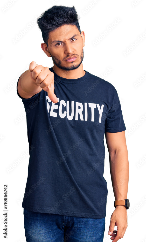 Wall mural Handsome latin american young man wearing security t shirt looking unhappy and angry showing rejection and negative with thumbs down gesture. bad expression.