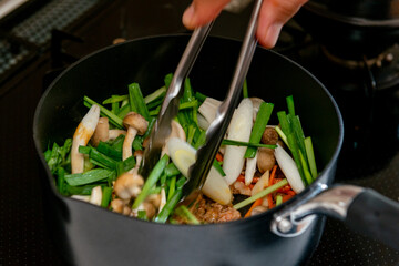 調理風景,鍋で野菜を炒める手元